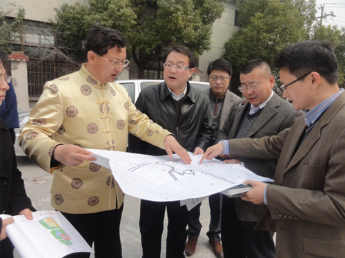 巨天中先生严谨细致地与企业领导查看地形布局图纸